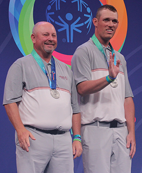 Dennis Gaines and Wake Mullins receive their silver medals at the 2022 Special Olympics USA Games. Mullins is waving to the crowd.