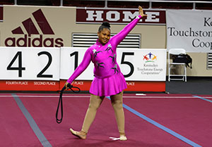 Rhythmic gymnast poses and smiles at the end of her rope routine.