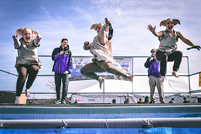 Three Louisville Polar Plunge Participants dressed as house elves from the Harry Potter stories jump into the pool in various poses.