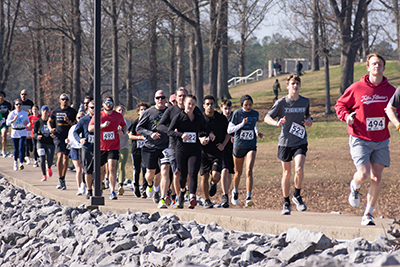 A pack of runners on a path above the rocks that line the lake early in the 2023 Polar 5k.