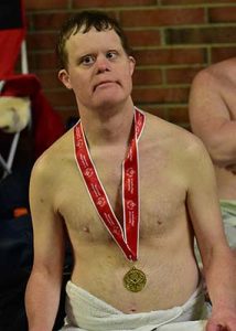 Brad Harkleroad sits with a towel around his waist and a swimming gold medal around his neck at the 2019 State Summer Games.