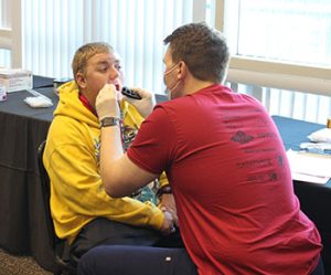 A volunteer dental worker looks at a Special Olympics athletes teeth.