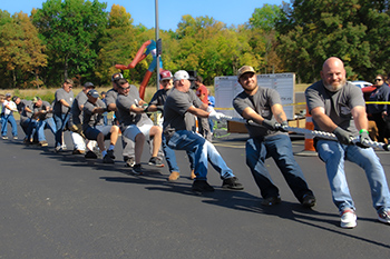 A group of men pulls a rope from the right side of the frame to the left.