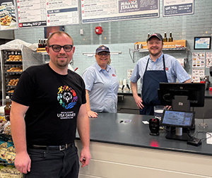 Athlete in a USA Games shirt visiting Jersey Mike's location with Jersey Mike's team members.