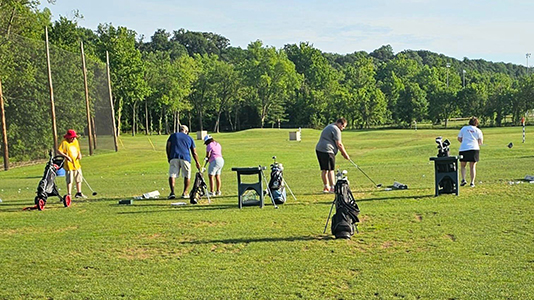 Athletes and a coach on the driving range at the 2024 Lexington Regional Golf Tournament.