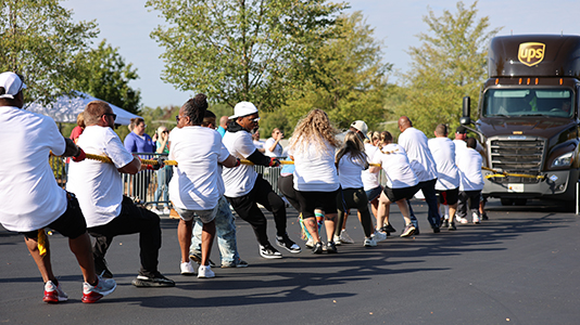 A team in white T-shirts pulls a UPS 18-wheeler at the 2024 Louisville Truck Pull