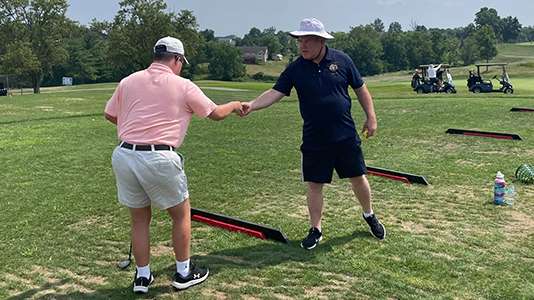 A volunteer hands a player a ball at the skills competition at the 22024 Northern Kentucky Regional Golf Tournament
