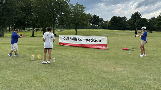 An athlete takes a swing during the Skills Competition while a volunteer and an official look on at the 2024 Western Kentucky Regional Golf Tournament