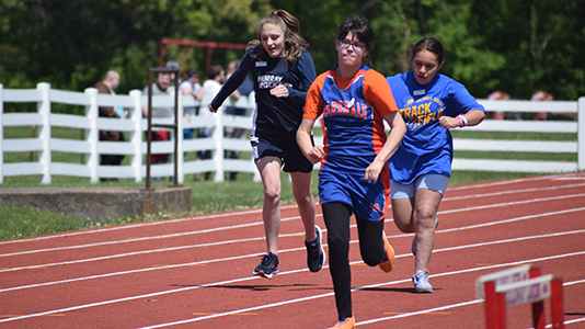 Three female athletes run down the front stretch at the 2024 Area 1 Track and Field Meet