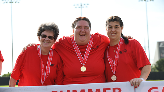 Three female athletes smiling and wearing their medals.