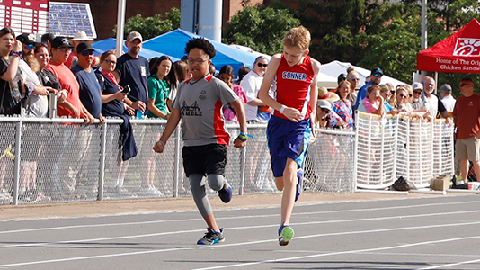 Two young athletes run down the track.