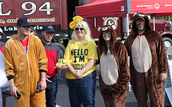 A group dressed like Goldilocks and maybe two and a half bears being presented a trophy.