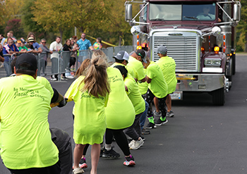 People pulling an 18-wheel truck with a rope.