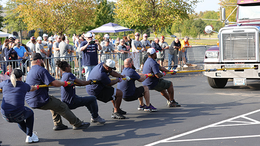 People pulling an 18-wheel truck with a rope.