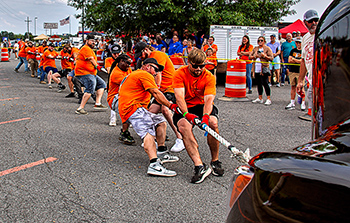 Men pulling a truck with a rope.