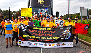 People holding various signs including a Paducah Truck Pull Event sign in front of an 18-wheeler.