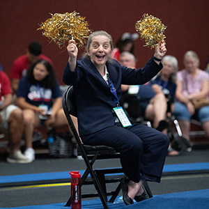 Tonya Cornett waving gold pom pons over her head.