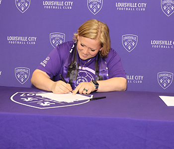 Anna Murray signs her commitment form at the Louisville City FC Unified Soccer Team announcement.