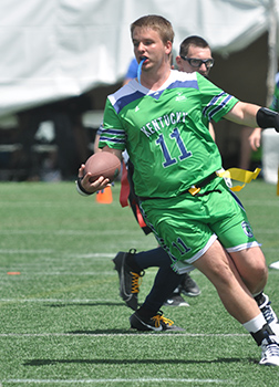 Football player in a green uniform running with the football.