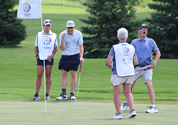 Chris Revay celebrates making a big putt as his caddy and others look on.
