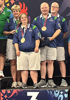 Bocce team on medal stand with bronze medals.
