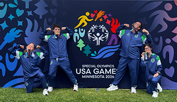 Track team striking poses in front of a USA Games banner.