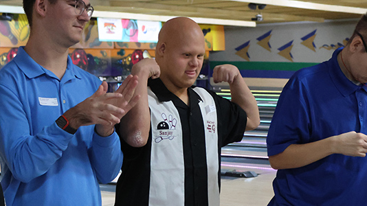 Bowler standing on the lane flexing while he waits for his award.