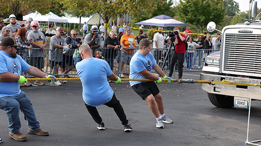 Men pulling a truck with a rope.