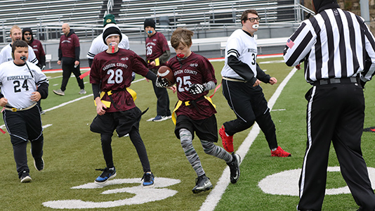 Football player running with the b all avoiding defenders.