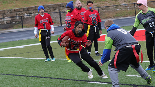 Football player running with the ball trying to evade defenders.