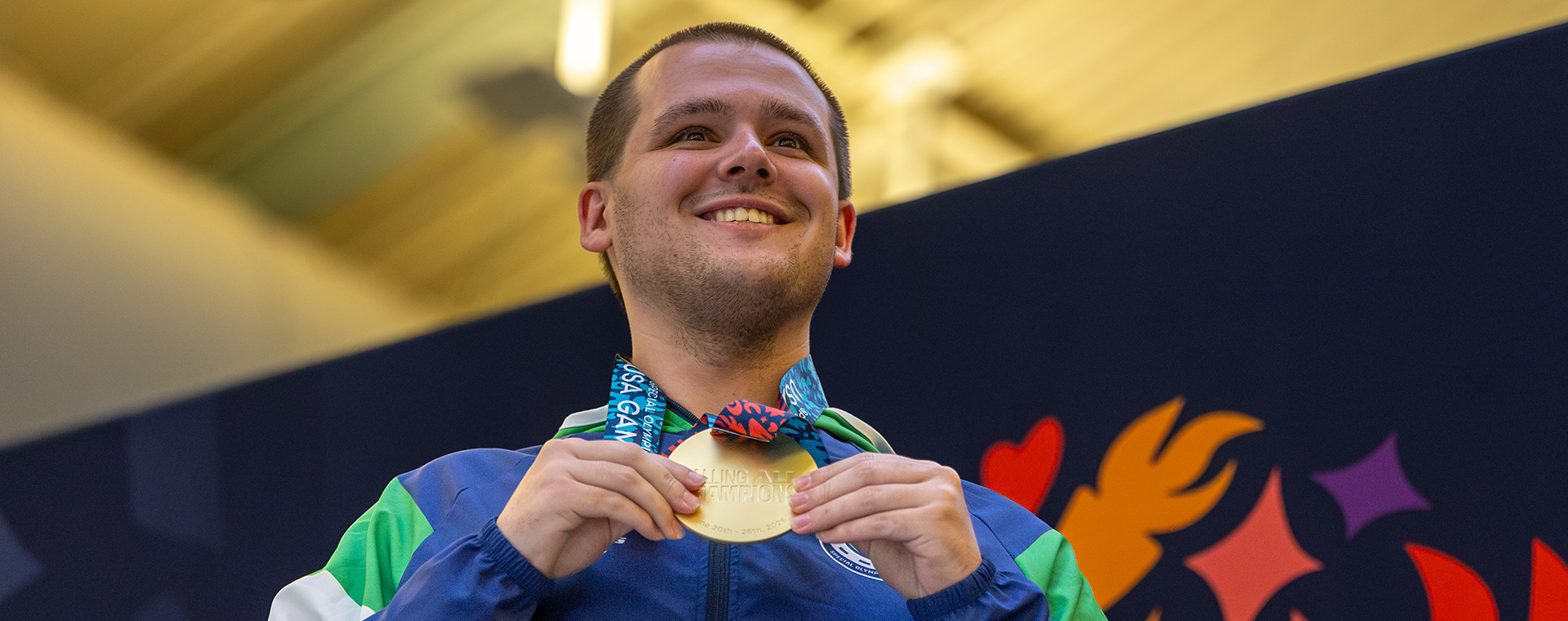 Justin Hale showing his gold medal on the medal stand.