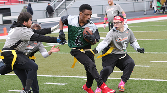 Football player running with the ball trying to avoid defenders.